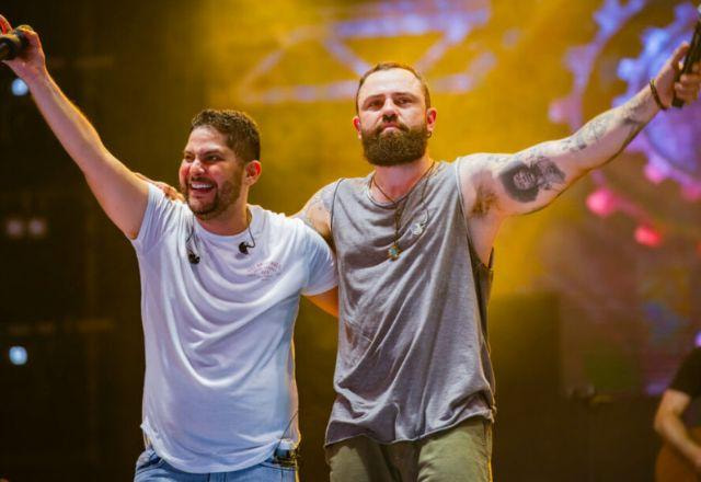 Jorge e Mateus com os braços abertos em um show