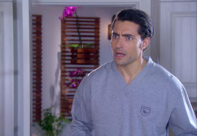 Gustavo Lários na cozinha e de pijama mescla, com expressão de desesperado