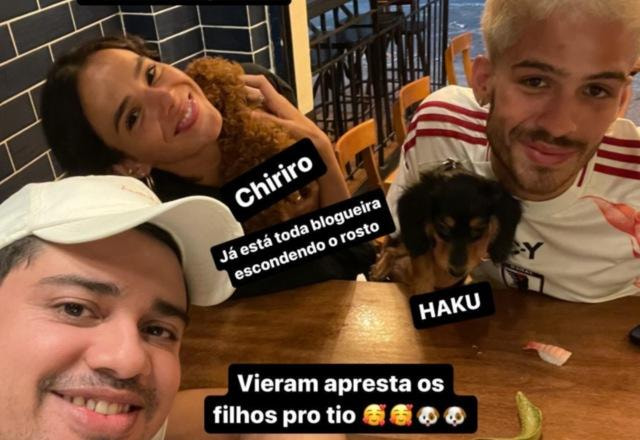 Foto onde estão Bruna Marquezine, João Guilherme e Maciel Paiva, sentados em uma mesa de restaurante, com dois cães no colo