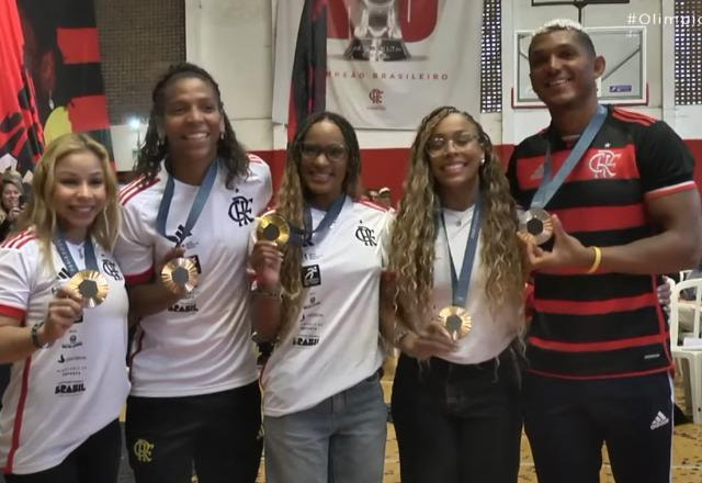 Foto com os medalhistas Rebeca Andrade, Jade Barbosa, Flávia Saraiva, Lorrane Oliveira, Rafaela Silva e Isaquias Queiroz, todos vestidos com uniforme do Flamengo e segurando a medalha olímpica