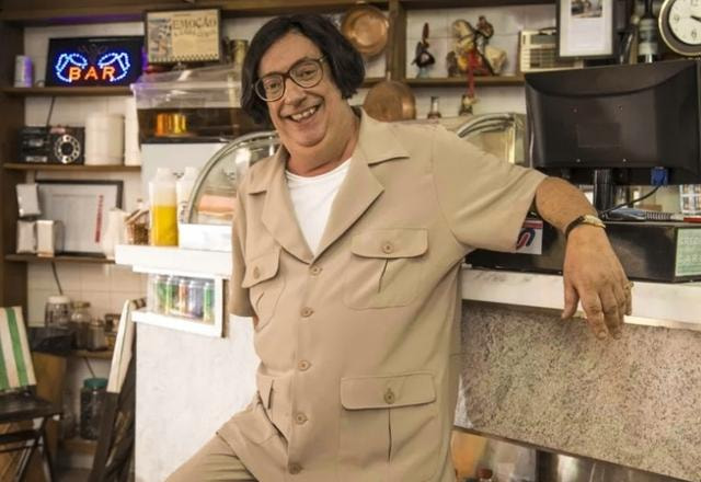 O ator Marcos oliveira de pé próximo a um balcão do que parece ser um bar. Esta caracterizado como o personagem Beiçola