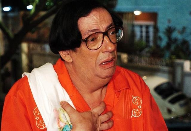 Foto de Marcos Oliveira, ator que interpreta Beiçola, vestido com uma roupa laranja e com expressão triste