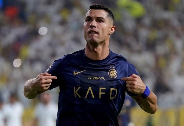 Foto de Cristiano Ronaldo com uma camisa azul de time de futebol, em campo e apontando para si mesmo