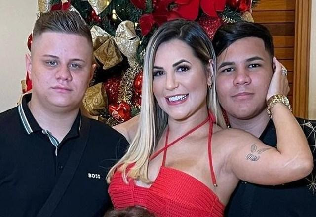 Imagem de Deolane Bezerra, vestida de vermelho, ao lado dos filhos Kayky Bezerra e Giliard Bezerra