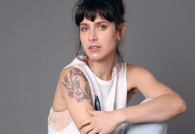 Foto de Mel Lisboa vestida de branco, com a tatuagem no braço a mostra e um piercing no nariz