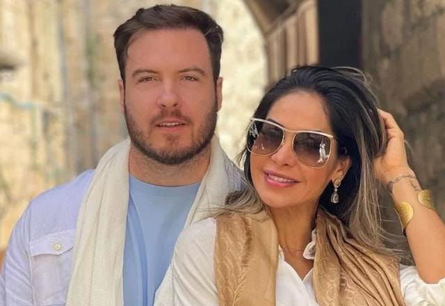 Foto de Thiago Nigro junto com a esposa Maíra Cardi, com Thiago de camisa azul e Maíra de óculos escuros