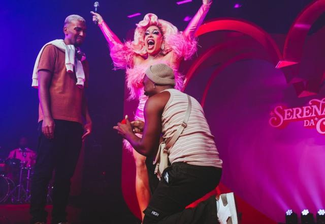 Foto de Gloria Groove em palco da turnê Serenata GG com casal de fãs se pedindo em namoro