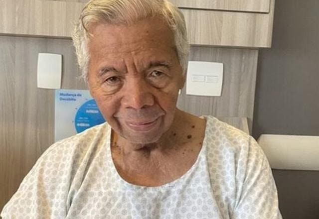 Foto de Roque vestido com roupa de internação hospitalar, aparentemente bem idoso