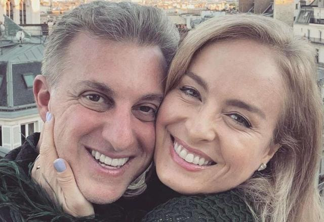 Foto de Angélica sorrindo e segurando o rosto de Luciano Huck
