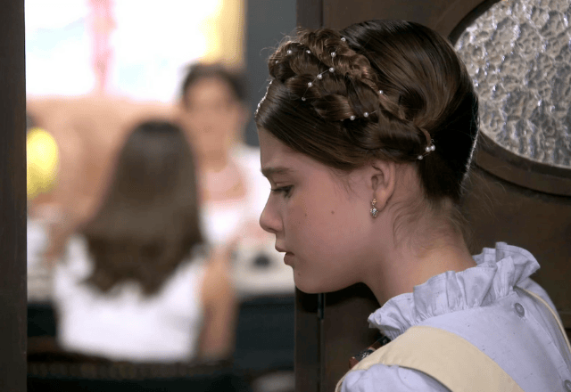 Lavínia escutando conversa atrás da porta