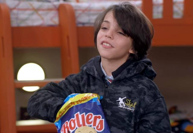 Senor usando um casaco preto e comendo salgadinho