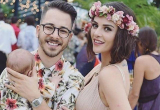 Junior Lima e sua esposa Monica Benini com sua filha no colo sorrindo para foto