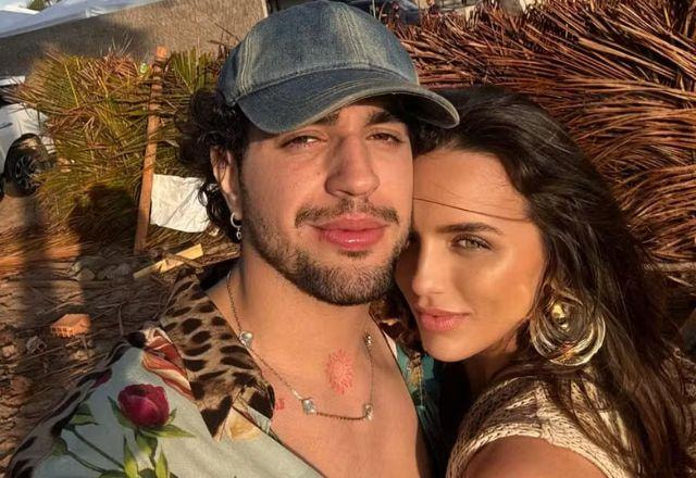 Cantor Nattan e influenciadora Rafa Kalimann, posam para selfie, ambiente ao ar livre com exposição ao sol