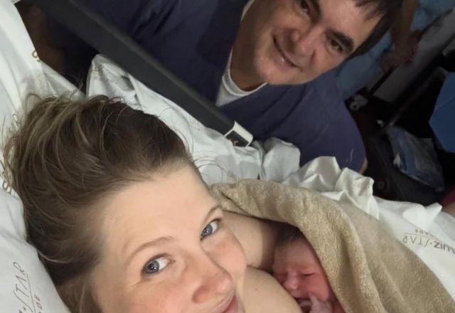 Samuel Rosa posa ao lado da esposa Laura Sarkova, que segura a filha Dora recém-nascida nos braços.