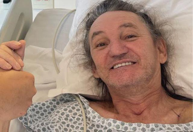 Marquito sorri para foto com roupa de hospital.