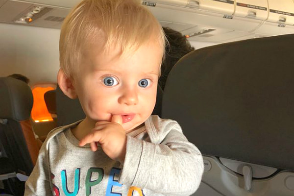 Com o dedo na boca, Enrico Bacchi olha com cara de quem vai aprontar muito no avião