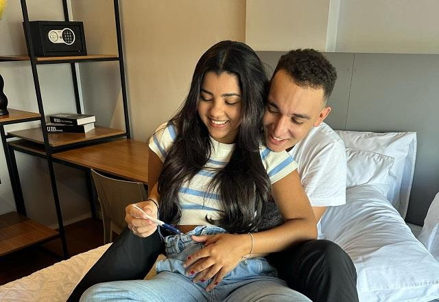 João Gomes e Ary Mirelle posam juntos abraçados, sorrindo e segurando teste de gravidez