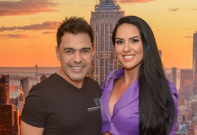 Graciele Lacerda e Zezé Di Camargo posam em frente à foto de um prédio